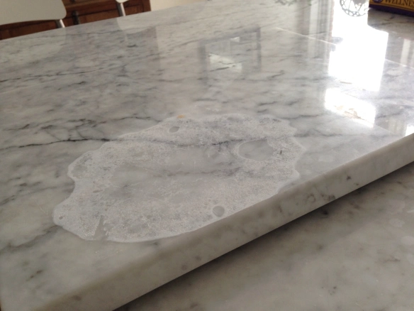 Stained marble countertop in a kitchen with poor lighting